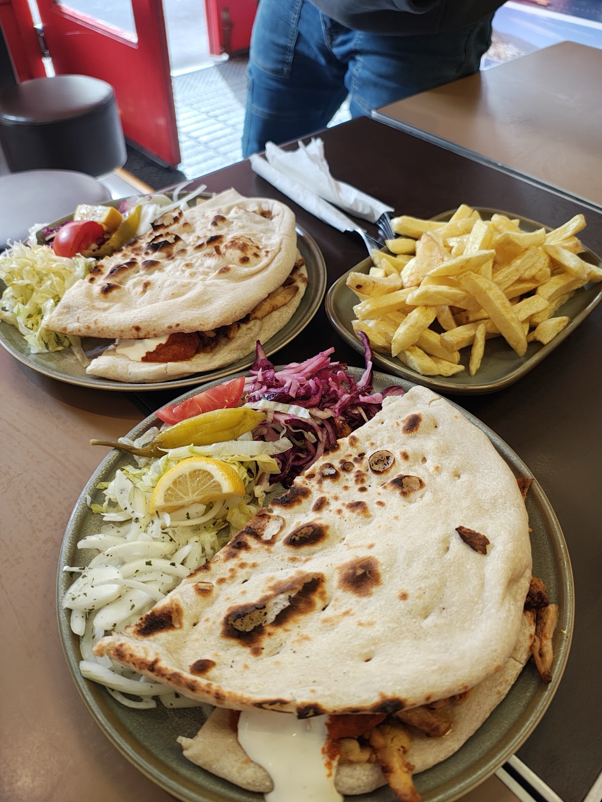 Two loaded kebab plates and a plate of chips on a table
