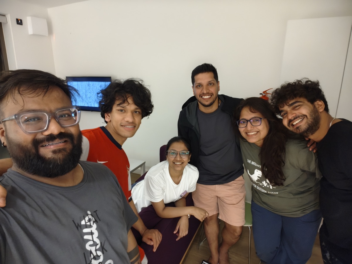 A group of six friends smiling together in a shared accommodation room